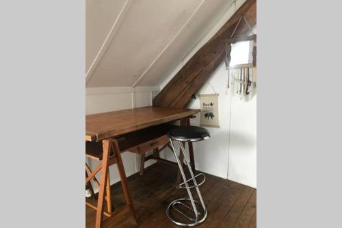 - un bureau en bois dans le grenier avec un tabouret dans l'établissement LES HORTENSIAS Spacieuse Maison en ardoise du pays FIBRE, à Voutezac