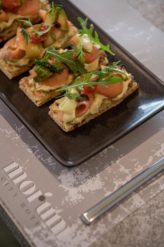 a black plate with three slices of pizza on it at Morum City Hotel Chania in Chania Town