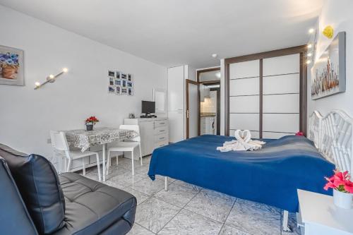 um quarto com uma cama azul e um sofá em OLYMPIA APARTMENTS em Playa de las Americas