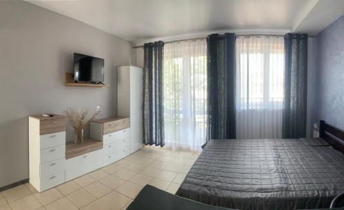 a bedroom with a bed and a tv and curtains at Апартаменти Маяк in Odesa