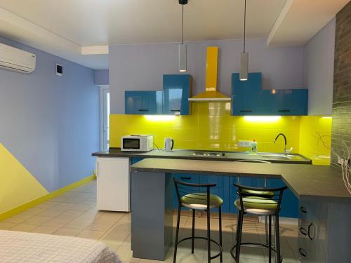a kitchen with blue cabinets and a counter with stools at Апартаменти Маяк in Odesa