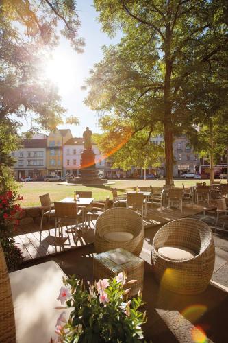 a park with tables and chairs and a statue at Vienna House by Wyndham Thüringer Hof Eisenach in Eisenach