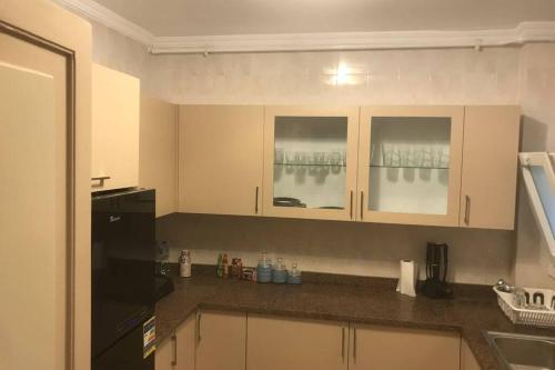 a kitchen with white cabinets and a black refrigerator at Executive 2 BedRoom Hotel Apmt Contactless check-in Premium Services and Quality at Madinaty in Madīnat ash Shurūq