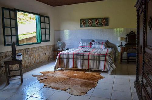 a bedroom with a bed with a blanket and a rug at Hotel Fazenda Pirapetinga 