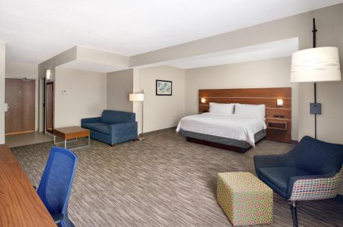 a hotel room with a bed and two chairs at Holiday Inn Express Statesboro by IHG in Statesboro