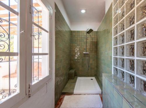 La salle de bains est pourvue d'une douche avec du carrelage vert et d'une fenêtre. dans l'établissement La Barranca de la Barca, à Alora