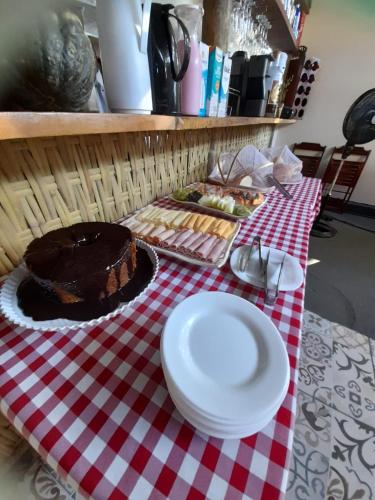 a table with a chocolate cake on a red and white table cloth at Pousada Água do Mar in Trindade