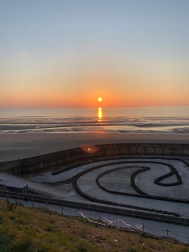 a sunset over the ocean with a clock in the sand at The Woodleigh family hotel in Blackpool