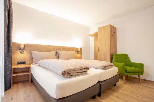 a bedroom with a bed and a green chair at Ferienwohnungen Tannenboden in Flumserberg