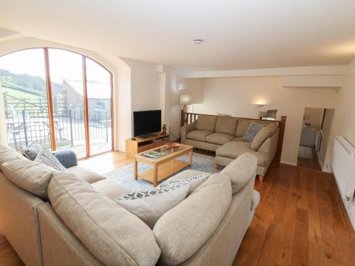 a living room with two couches and a tv at Broadwood Barn in Hathersage