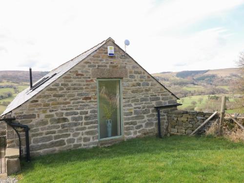 a small stone building with a window in a field at Broadwood Barn in Hathersage