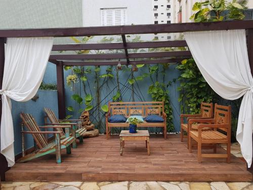 Hotel Casarão Pitangueiras في غوارويا: فناء فيه كراسي وطاولة ومقعد