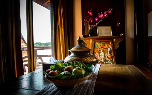 a bowl of fruit on a table with a vase at Ayutthaya Garden River Home in Ban Bang Krasan