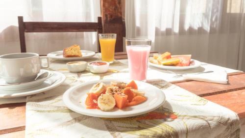 a table with a plate of food and drinks on it at Pousada Porto Da Barra in Porto Seguro
