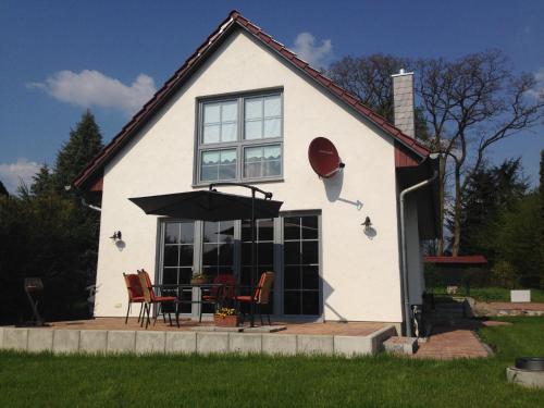 a white house with a table and chairs in front of it at Ferienhaus Scheune in Reichenwalde