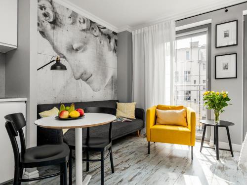 a living room with a table and a yellow chair at Happy Stay Tartaczna Residence I in Gdańsk