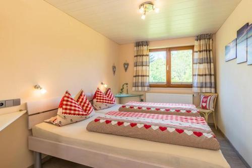 HergensweilerにあるFerienwohnung Obstwieseのベッドルーム1室(ベッド2台、赤と白の枕付)