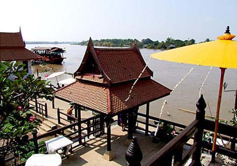 Ayutthaya Garden River Home في Ban Bang Krasan: مبنى فيه مظله صفراء بجانب الماء