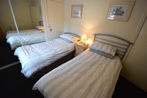 two beds in a room with a mirror at Armadale Cottage in Lochgoilhead