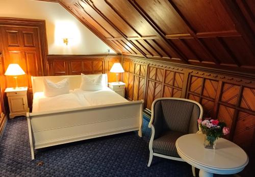 a bedroom with a bed and a chair and a table at Fürstenhof Wernigerode Garni in Wernigerode