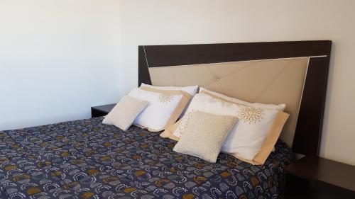 a bedroom with a bed with pillows on it at Apartamento Deluxe Senderos del Vino I, con cochera incluida, Desayuno opcional in Mendoza