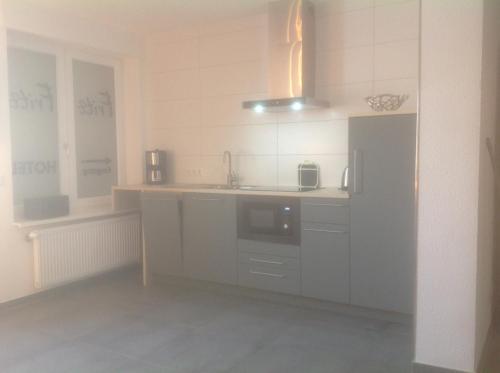 a white kitchen with a sink and a refrigerator at Hotel Restaurant Fritz in Gronau