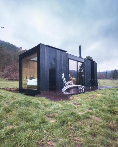 a black house in a field with a chair at Bleu Minuit L'Arche in Obersteinbach