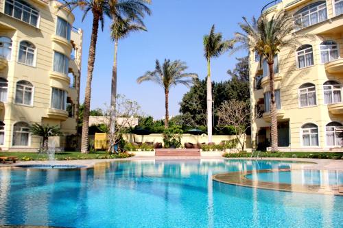 a swimming pool in front of a building with palm trees at Soluxe Cairo Hotel in Cairo