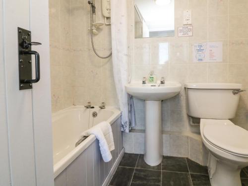 a bathroom with a sink and a toilet and a bath tub at The Stables in Holsworthy