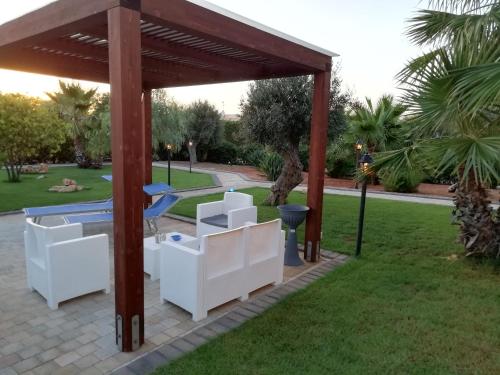 einen Pavillon mit weißen Möbeln in einem Park in der Unterkunft Il Corallo in San Vito lo Capo