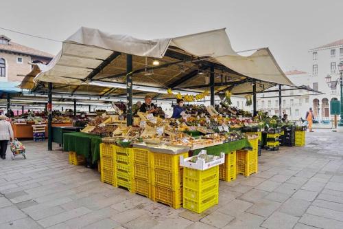 a market with yellow tables and people standing around them at Appartamento a Rialto, calle della Madonna in Venice