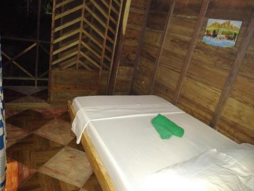 a small room with a bed with a green item on it at HOSTAL BELLEZA TROPICAL in Moñitos