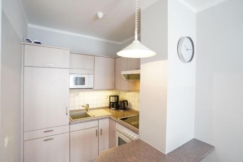 a kitchen with white cabinets and a clock on the wall at Ferienwohnung Garzmann in Bad Reichenhall