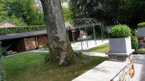a tree sitting next to a park with a metal structure at Le Prangeleux in Tenneville
