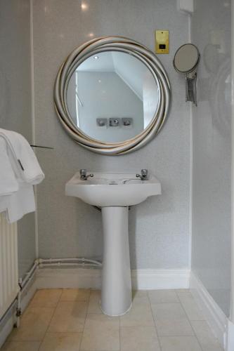 a bathroom with a sink and a mirror on the wall at The Hotel Commodore in Llandrindod Wells