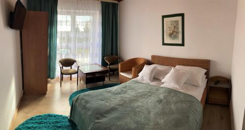 sypialnia z łóżkiem, krzesłem i stołem w obiekcie Willa Perełka w mieście Mielno
