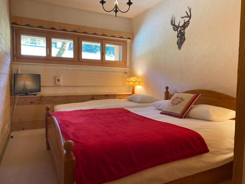 a bedroom with two beds with a red blanket at Apartment La Berciére 6 in Villars-sur-Ollon