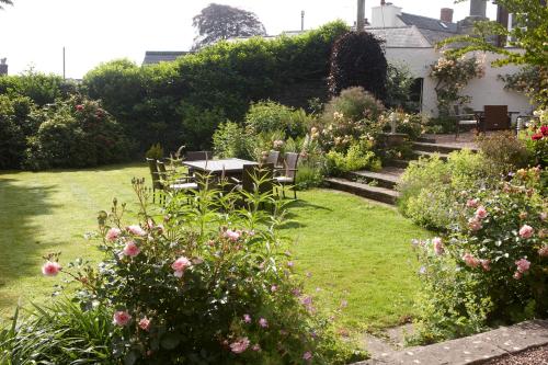 a garden with a table and chairs and flowers at The Arundell in Lifton