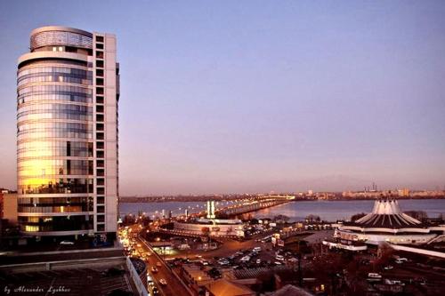 a tall building next to a river and a city at Staybridge Mini-Hotel in Most City PANORAMIC RIVER VIEW in Dnipro