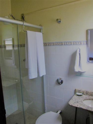 a bathroom with a shower and a toilet and a sink at Pousada das Bromélias in Serra do Cipo
