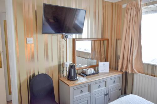 a bedroom with a desk with a tv on the wall at The Hotel Commodore in Llandrindod Wells