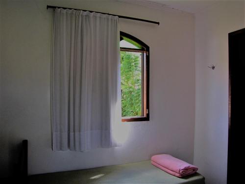 a room with a window and a pink pillow at Pousada das Bromélias in Serra do Cipo