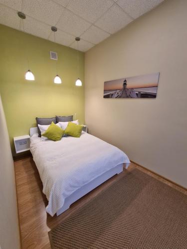 a bedroom with a large white bed with green walls at Center Apartments Tukums in Tukums