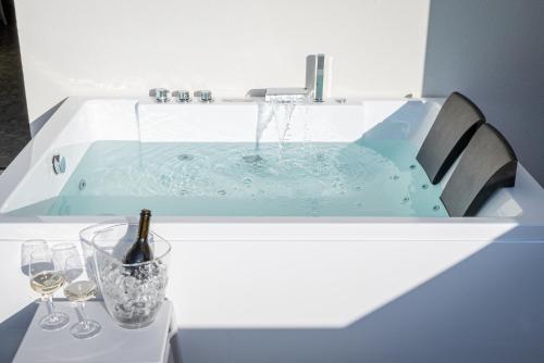 a bath tub with a bottle of wine and glasses at HOTEL TRILAGO in Trasaghis
