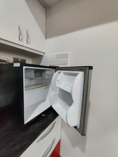 an empty refrigerator with its door open in a kitchen at Royal Wings Apartments in Mysore