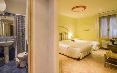 1 dormitorio con 2 camas y baño con lavamanos en Elisart Guest House, en Alghero