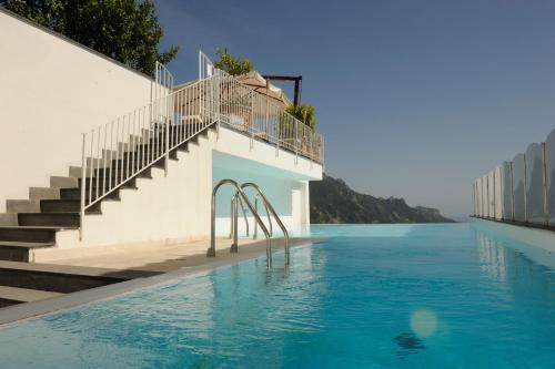 a swimming pool with stairs and blue water at Hotel Villa Fraulo in Ravello