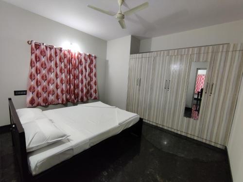 a bedroom with a bed with a red curtain at Royal Wings Apartments in Mysore