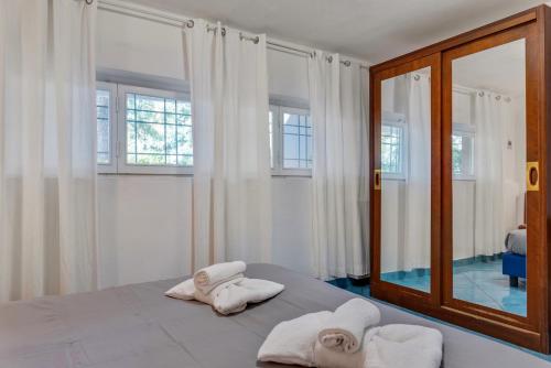 a bedroom with white towels on a bed with a mirror at InVilla Seristori, a 50 m dal mare in San Vincenzo