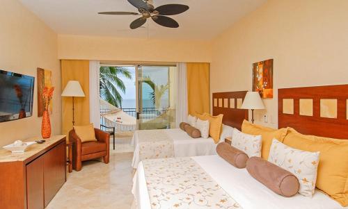 a hotel room with two beds and a television at Suites at Garza Blanca Preserve Resort & Spa in Puerto Vallarta